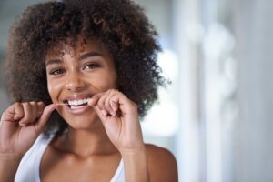 A young woman smiling while flossing her teeth
