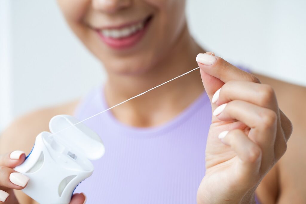 A woman pulls floss out of its packaging