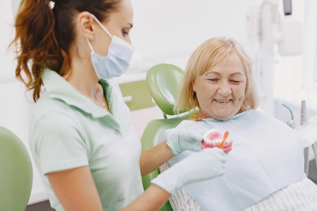 A female dentist giving oral health instructions to an elderly female patient