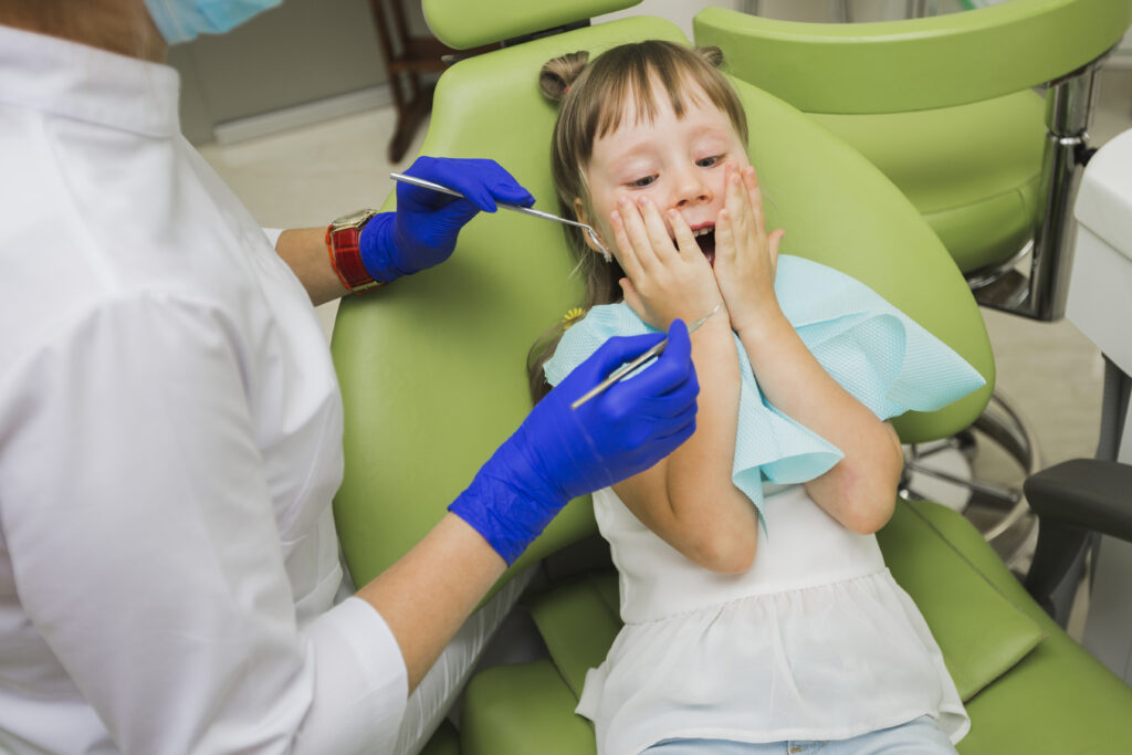 A young girl who is fearful and surprised at the dentist