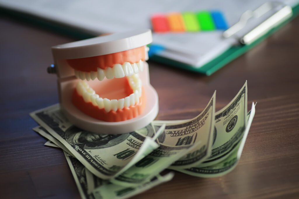 A denture sits on top of a stack of 100 dollar bills.