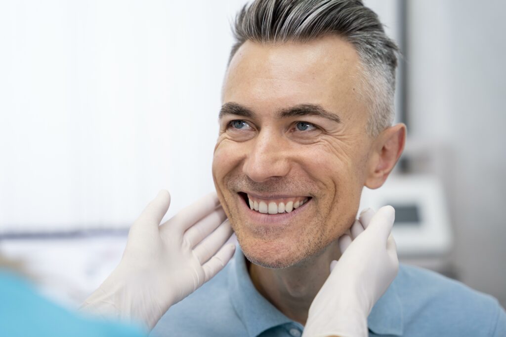 A silver-haired male patient undergoing an oral cancer screening