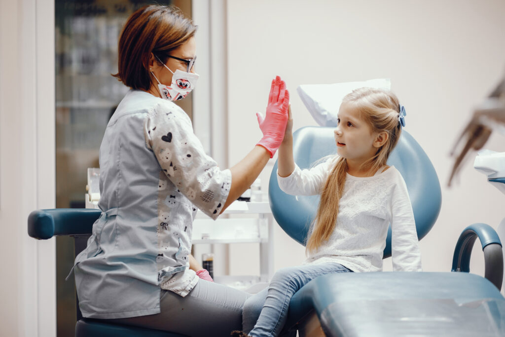 A female dentist high-fives a cute young female patient