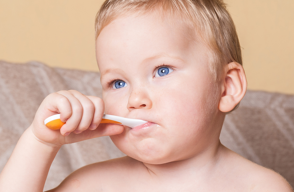 A young baby brushing his teeth with a toothbrush