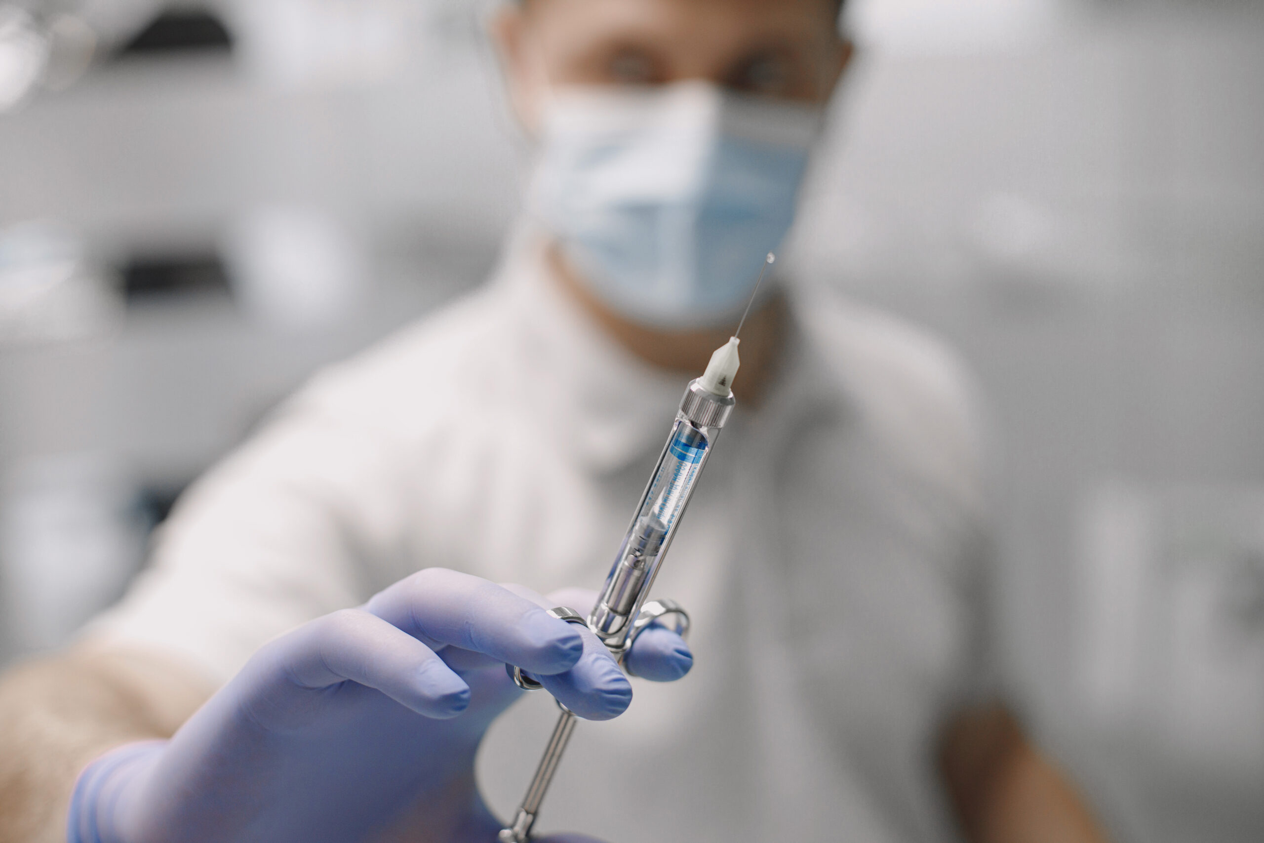 A dentist holds a syringe filled with Arestin