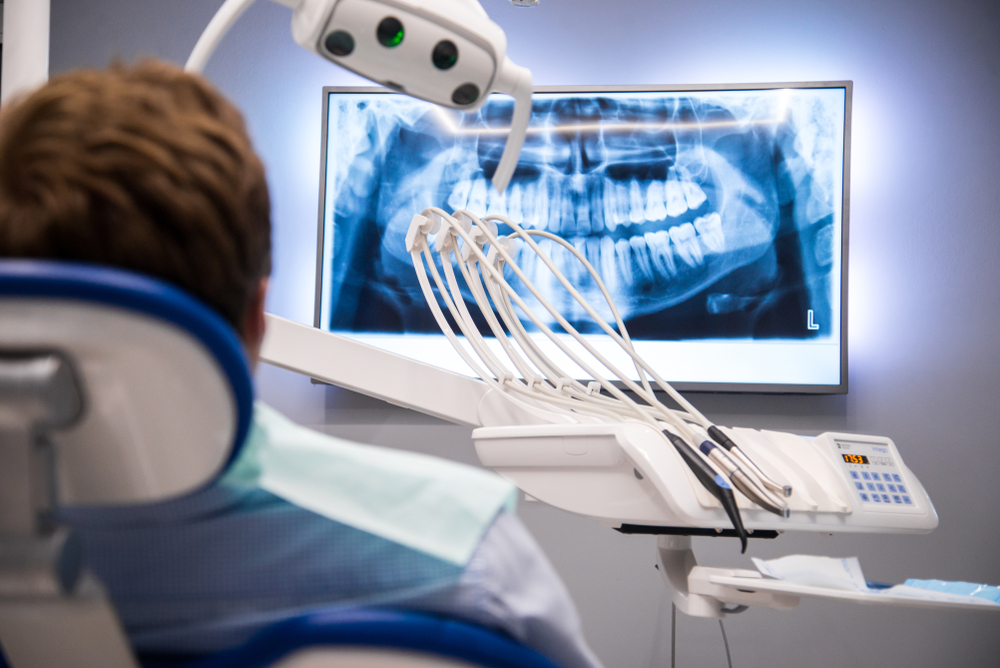 A male patient looks at dental x-rays from a dental chair