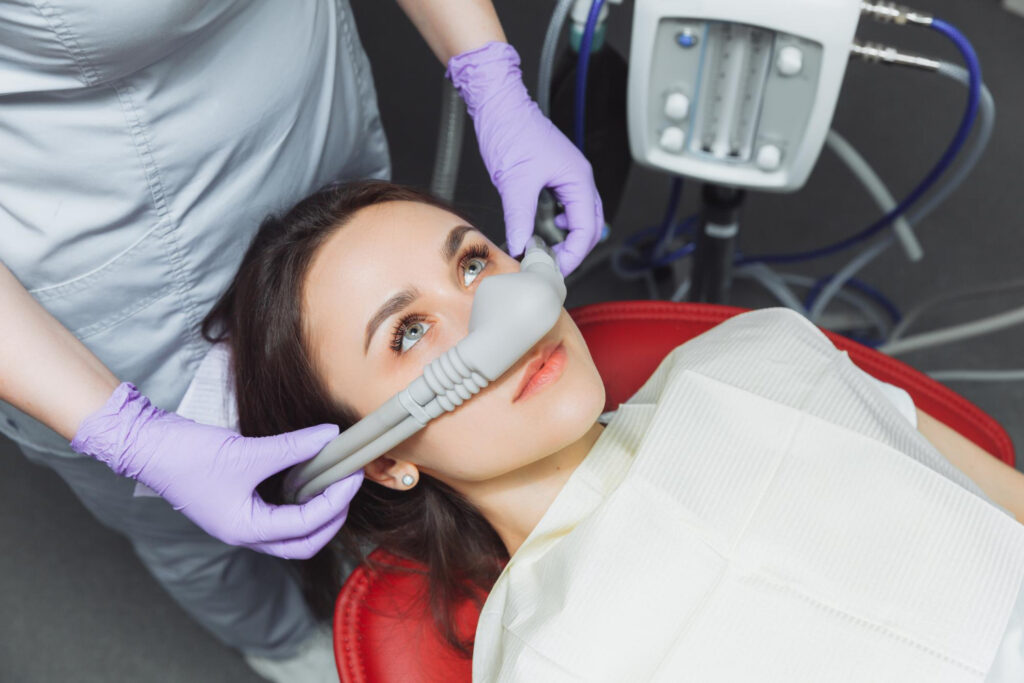 A dentist applies a nitrous mask to a female patient