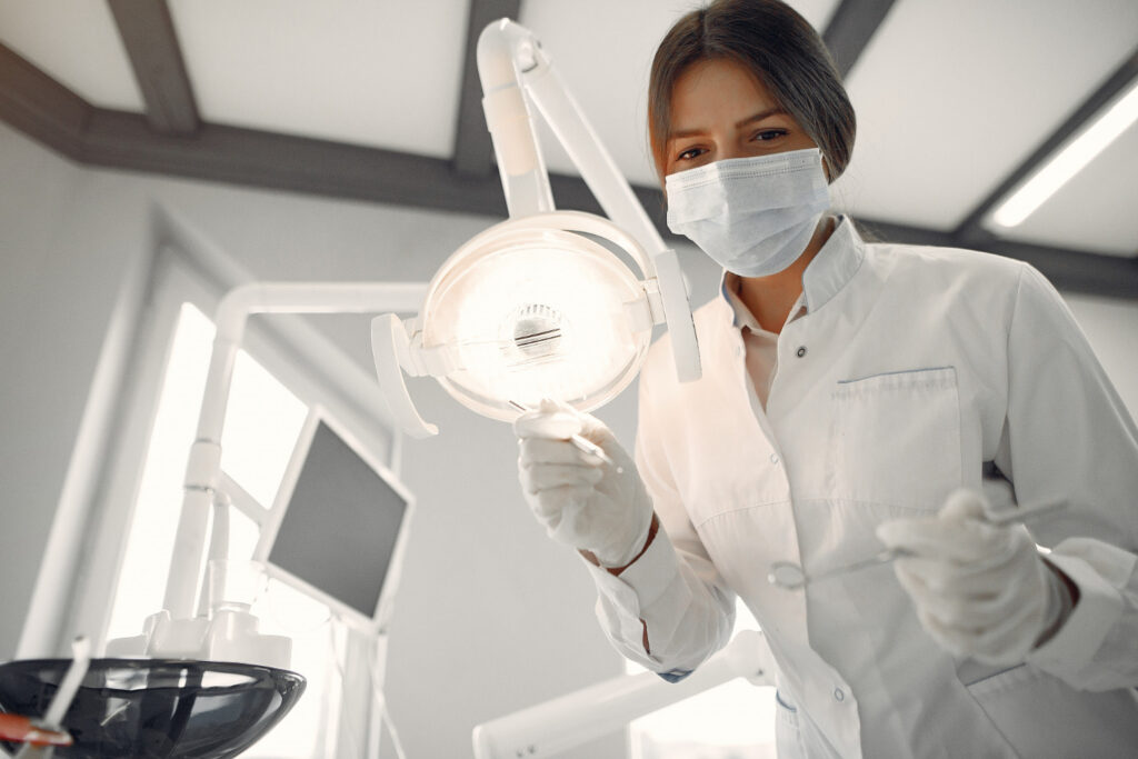 A dental hygienist stands over a patient