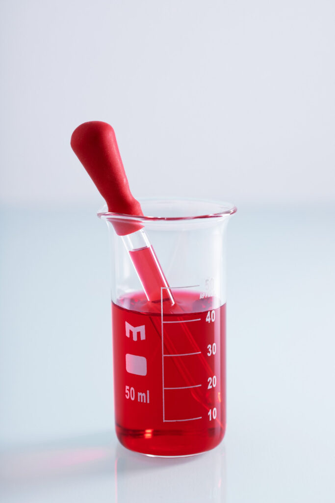 Dosing red fluid using a dropper inside a measuring cup