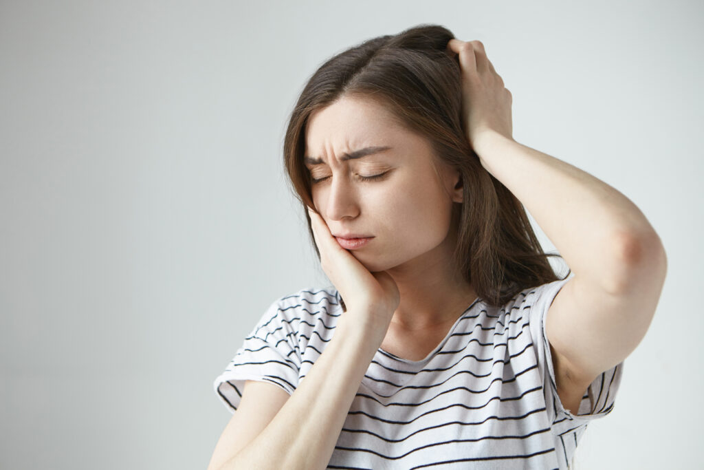 A woman with joint pain and headache due to TMJ Disorders