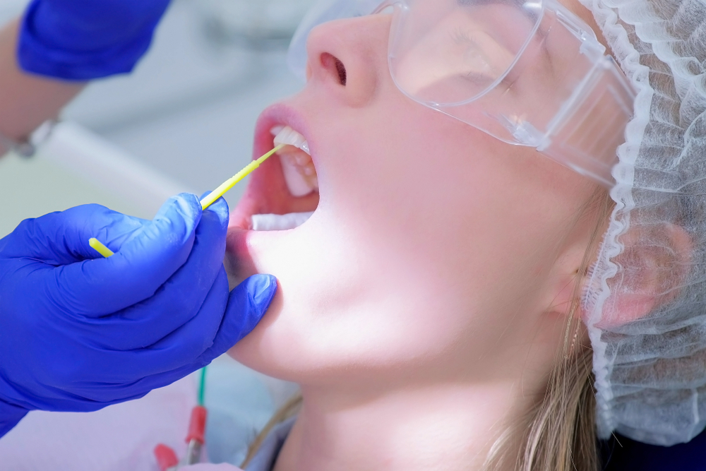 A dentist applies fluoride varnish to a patient
