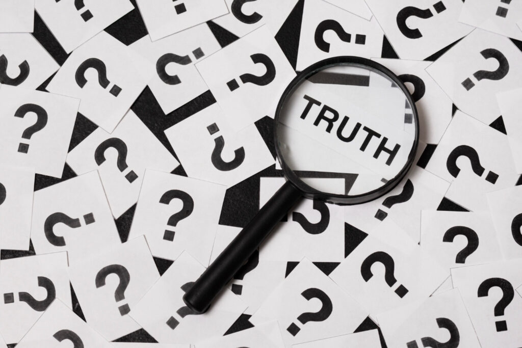A magnifying glass enlarges the word "Truth" on a flipped over card