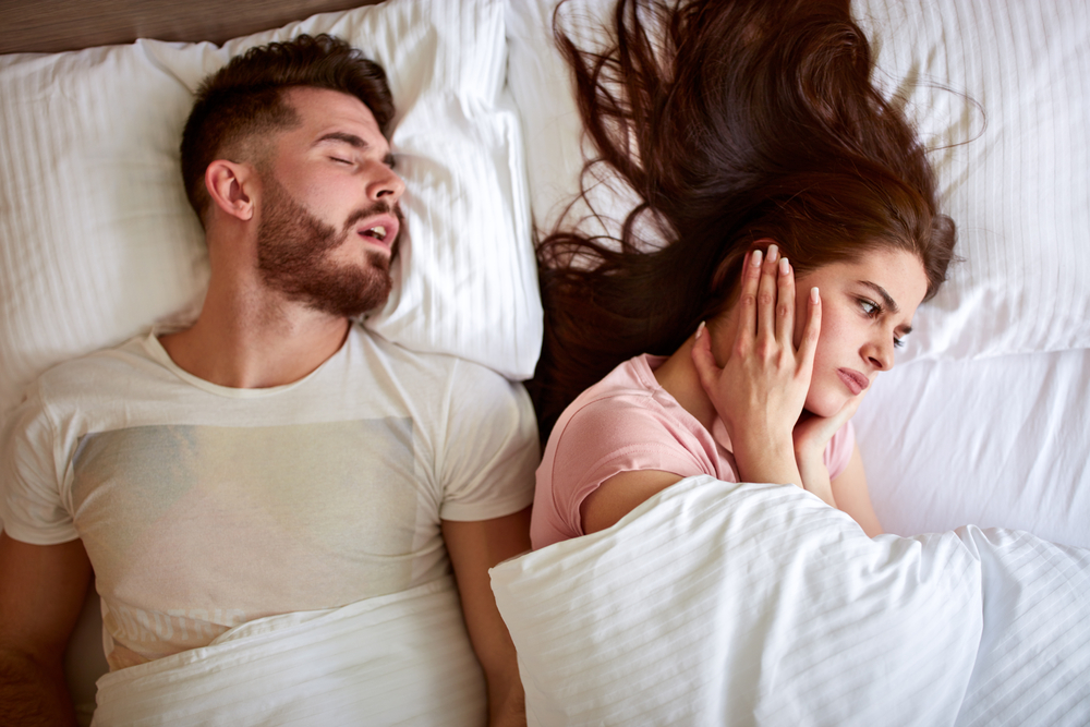 A man with Upper Airway Resistance Syndrome (UARS) is snoring - his female partner covers her ears