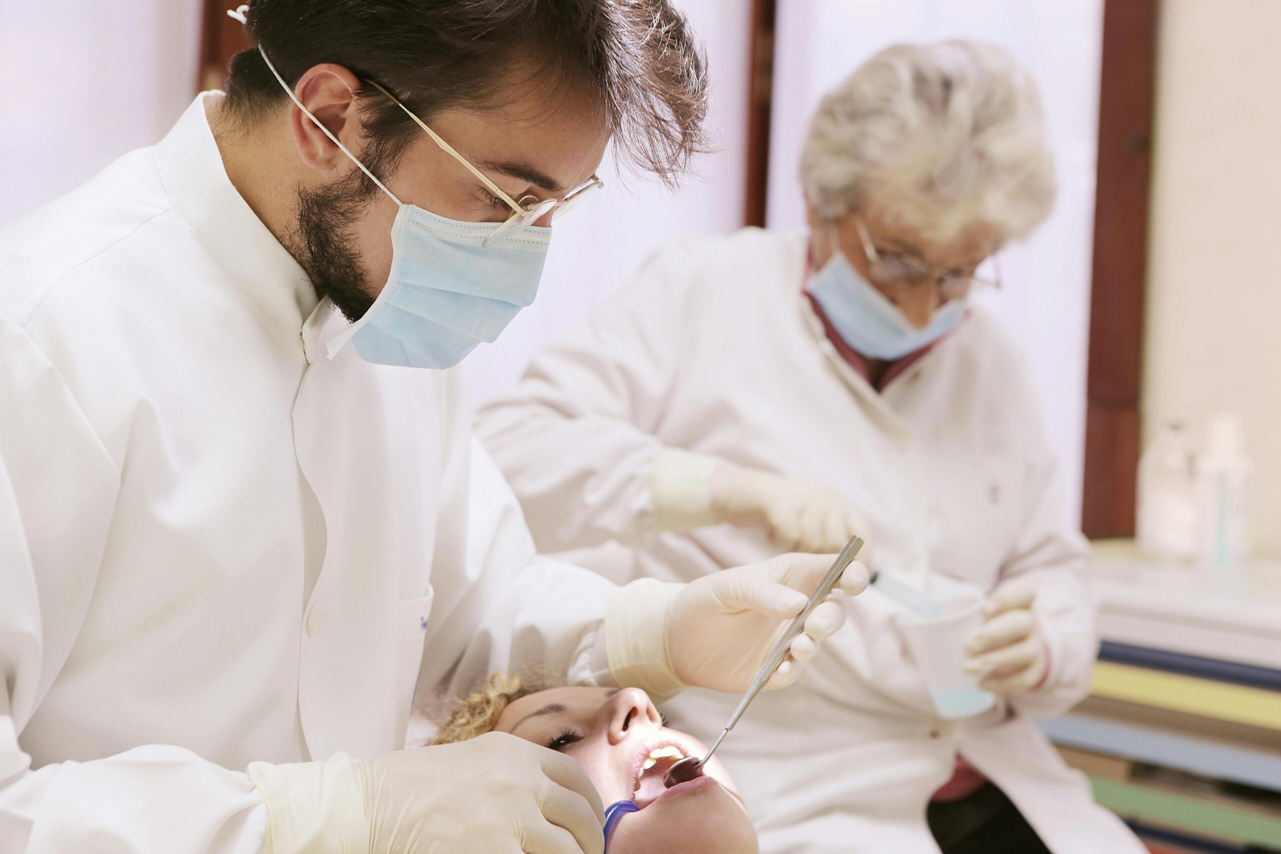 Dentist examining a patient's mouth with dental tools.