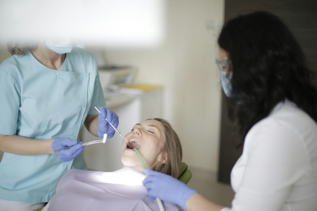 Dentists examining a patient's teeth in a clinic.