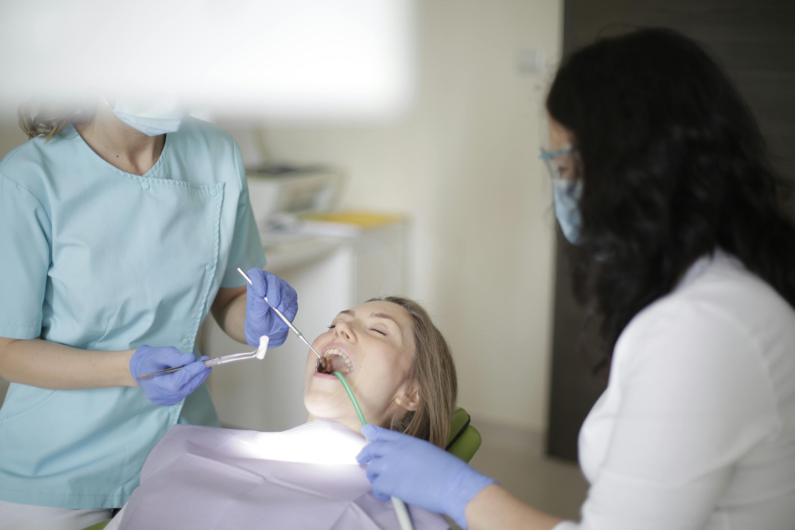 Dentists examining a patient's teeth in a clinic.