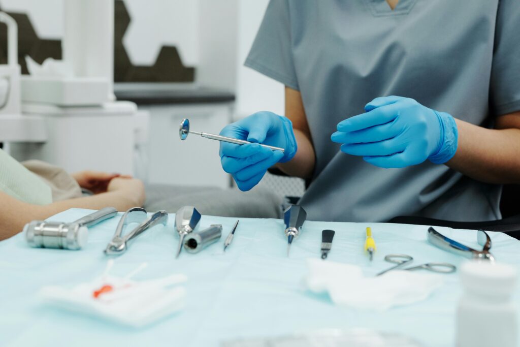 Dentist with gloved hands holding dental tools.