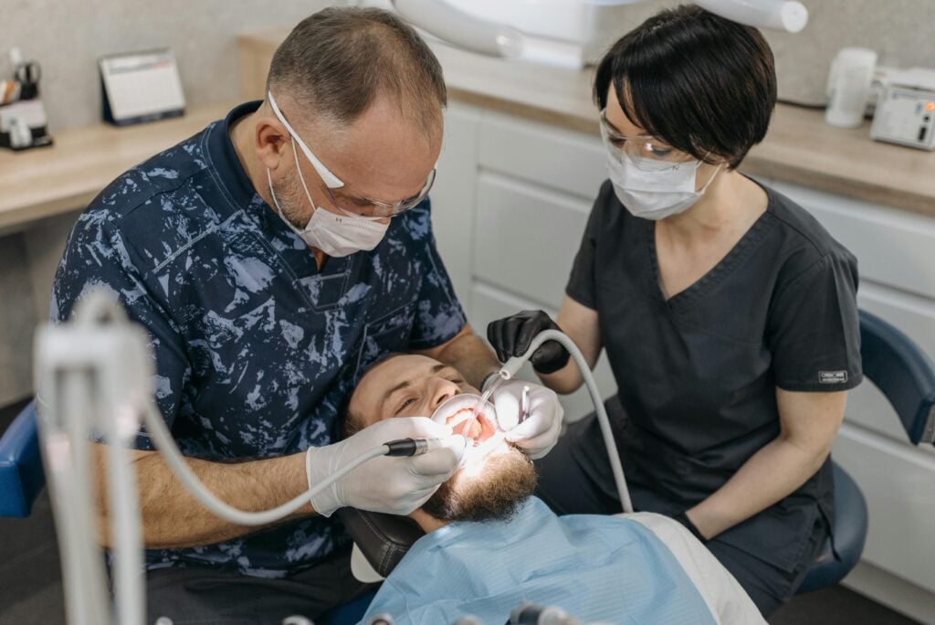 Dentist and assistant performing a dental procedure on a patient.