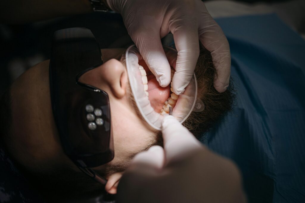 Dentist examining a patient's teeth with gloved hands.