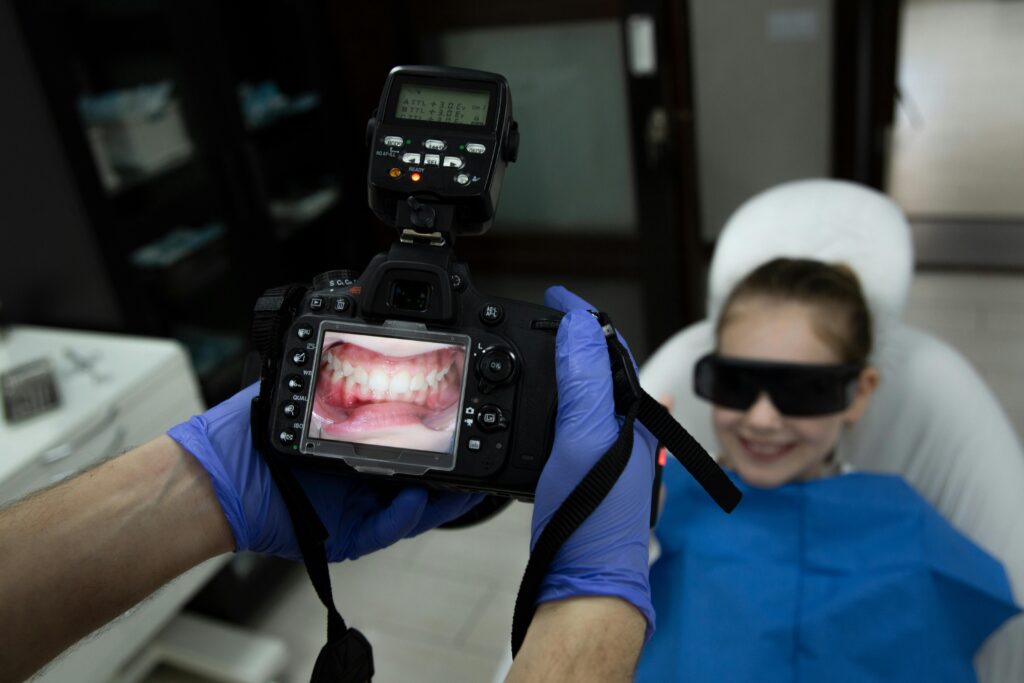 Dentist photographing a child's teeth during an exam.