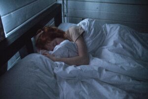 Person sleeping in bed under white sheets.