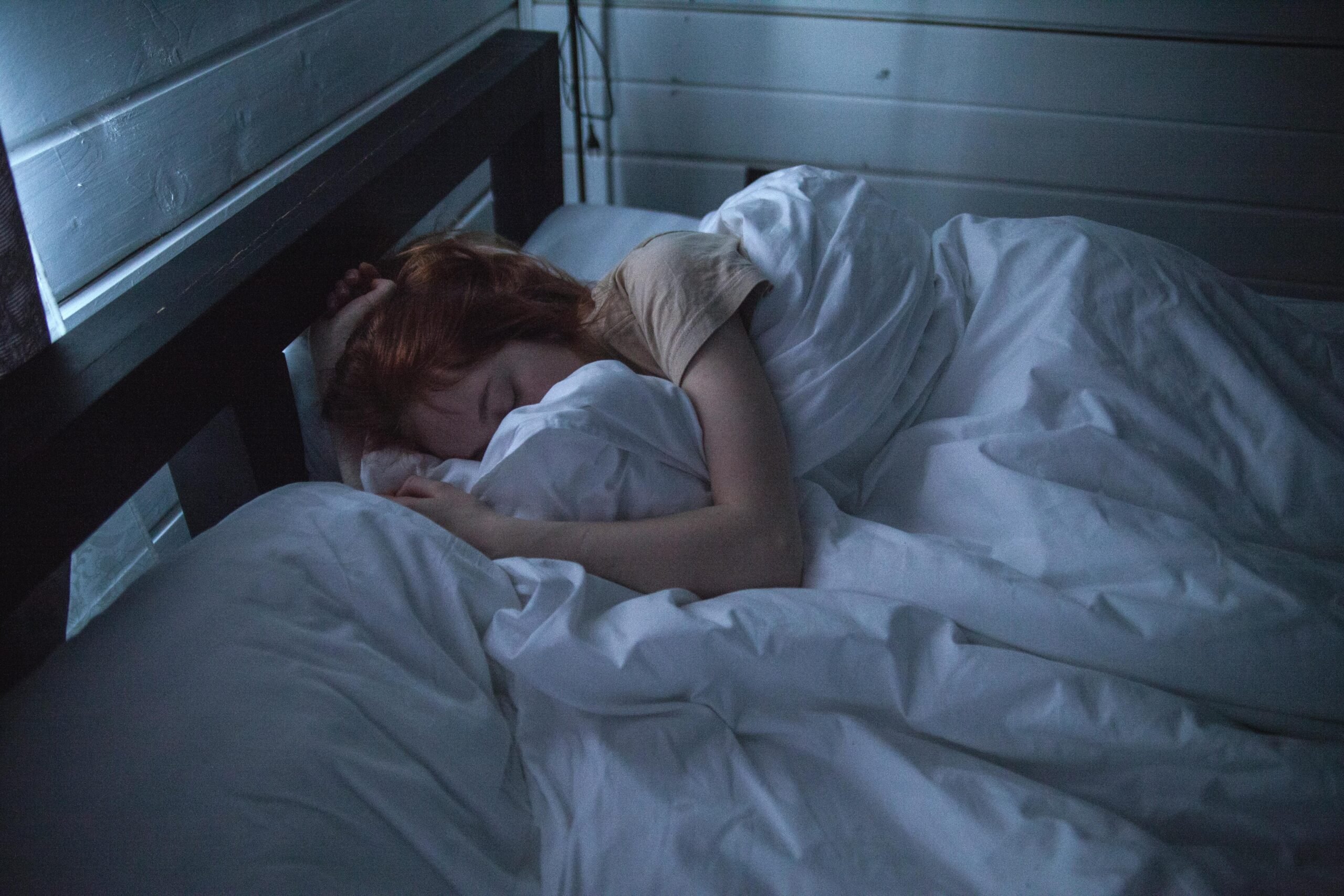 Person sleeping in bed under white sheets.