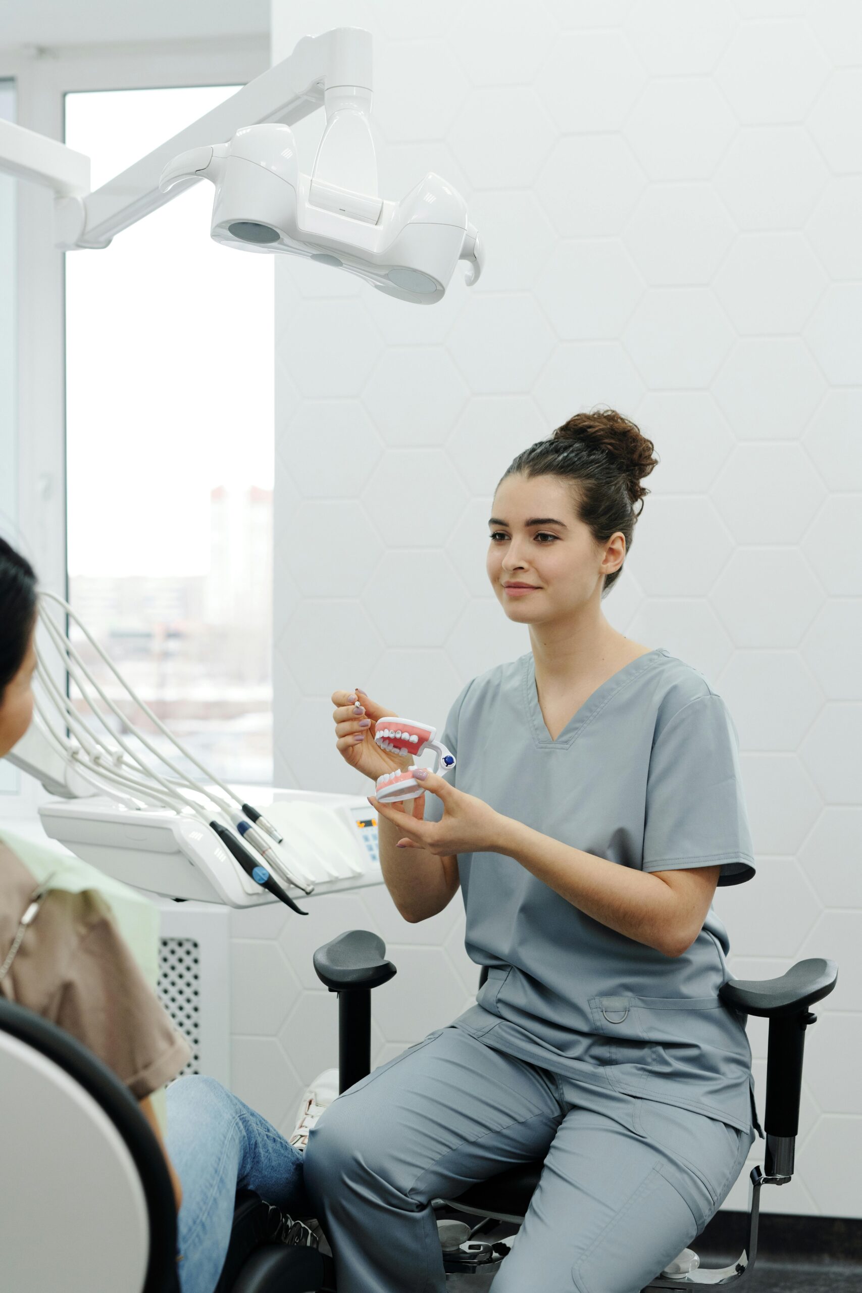 Dental professional showing a teeth model to a patient.