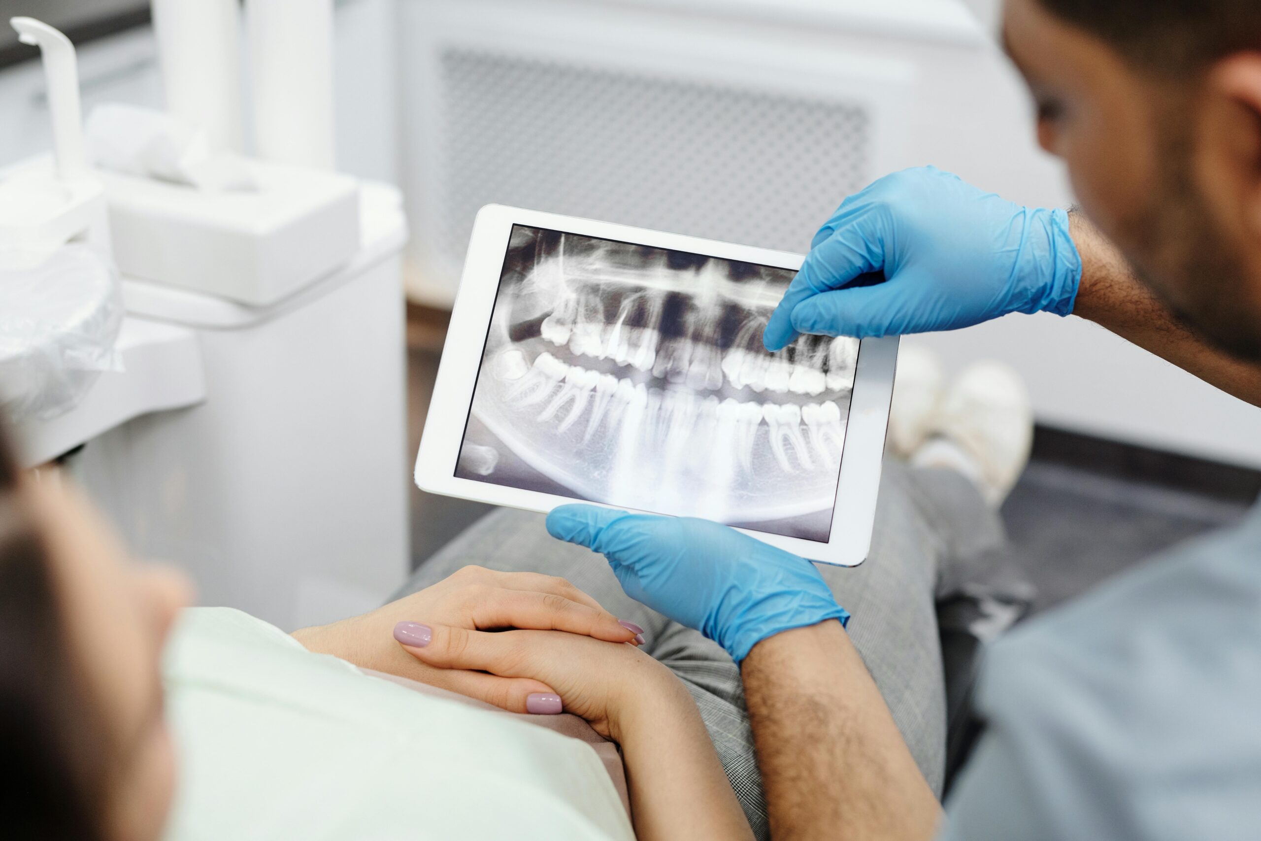Dentist showing dental X-ray on a tablet to a patient.