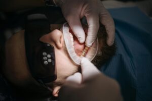 Dentist examining a patient's gums with gloved hands.