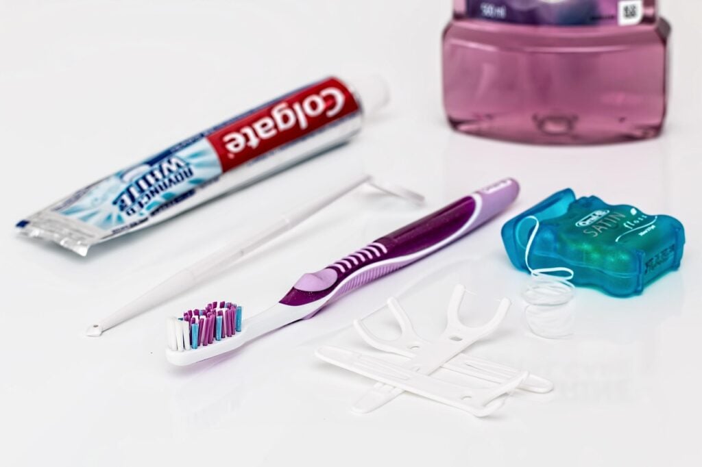 Toothpaste, toothbrush, and dental floss on a white surface.