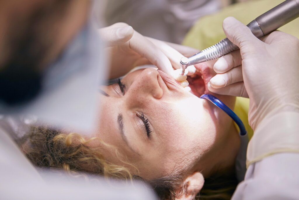 Dentist working on a patient's teeth with a dental tool.