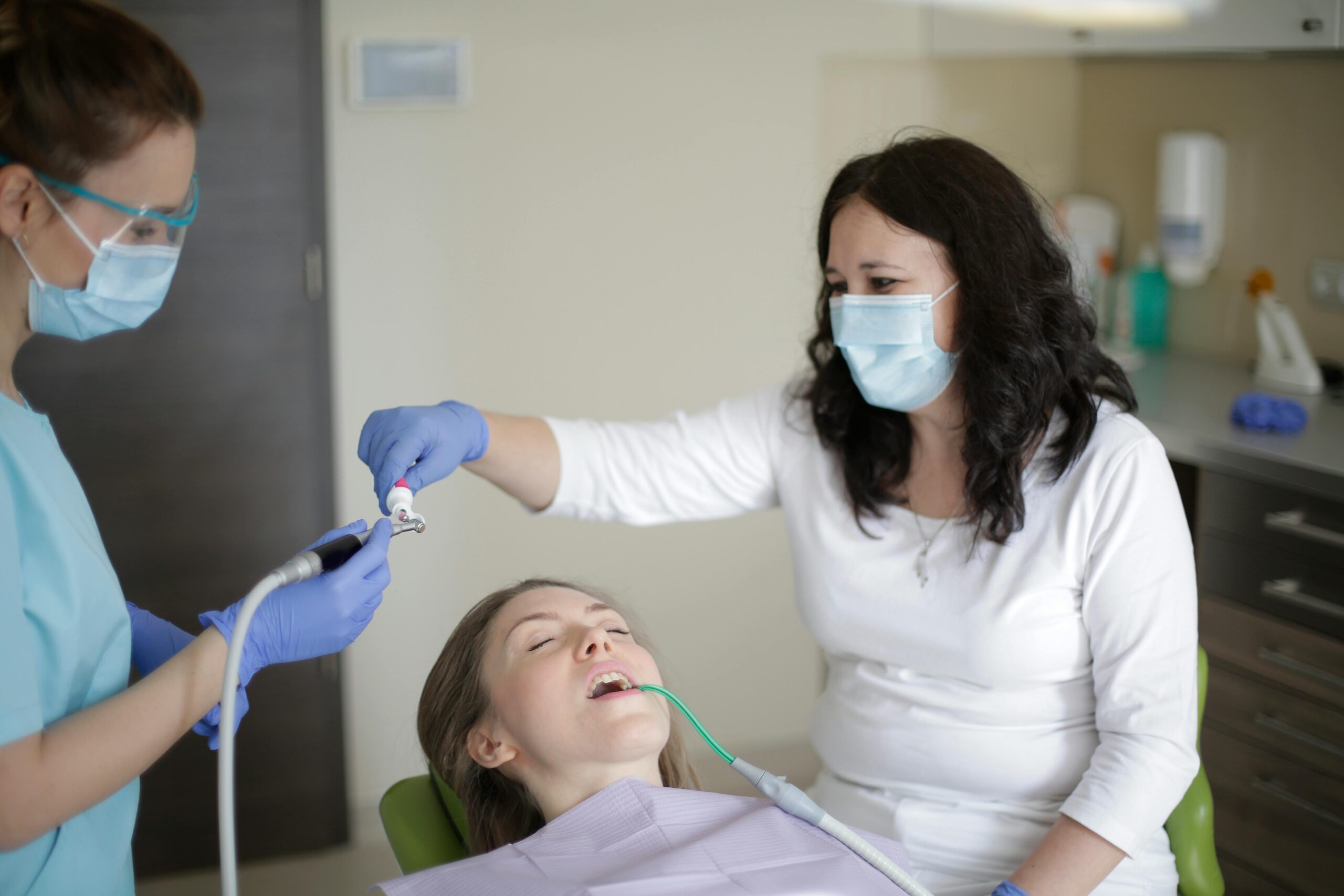 Dentist and assistant performing a cavity filling procedure on a patient.