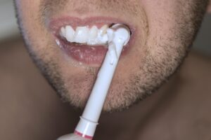 Close-up of a person brushing teeth with an electric toothbrush.