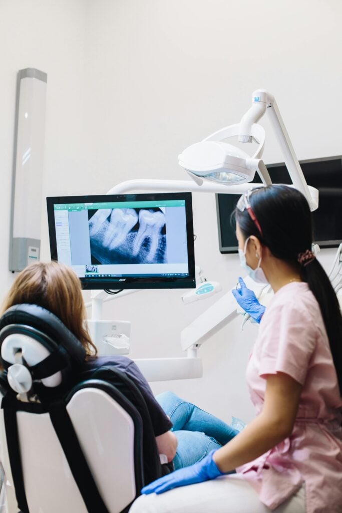 Dentist showing dental X-ray to a patient on a screen.