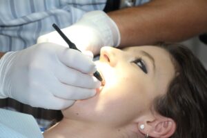 Dentist examining a patient's mouth with a dental tool.