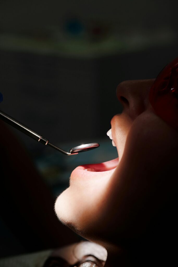 Dentist examining a patient's mouth with a dental mirror.