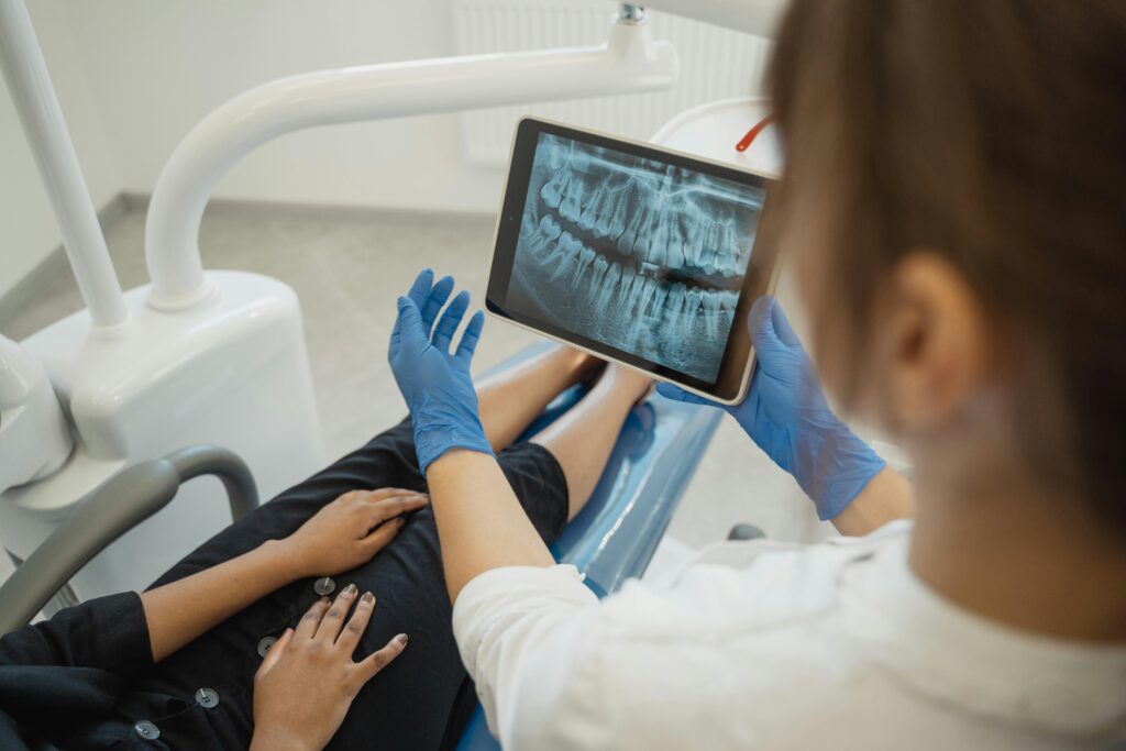 Dentist showing a dental X-ray on a tablet to a patient.