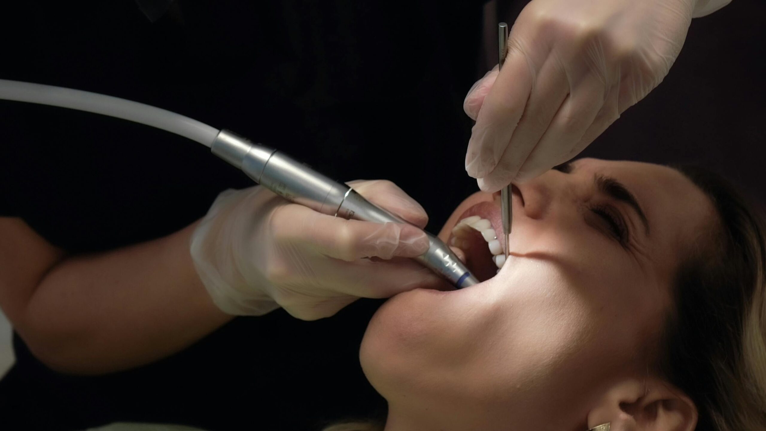 Dental hygienist using tools in a patient's mouth.