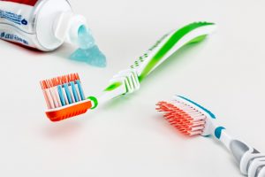 Adult toothbrushes and toothpaste on a white surface.