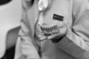 Dentist holding a dental model, illustrating denture vs implant.