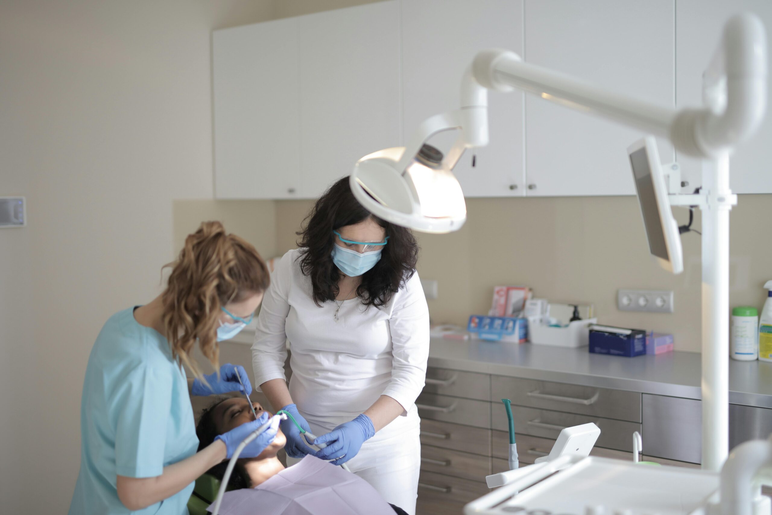 Two dentists performing a procedure on a patient in a clinic.
