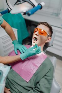 Dentist cleaning a patient's teeth with a dental tool.