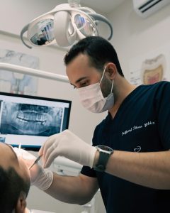 Dentist examining a patient with dental X-ray on screen.