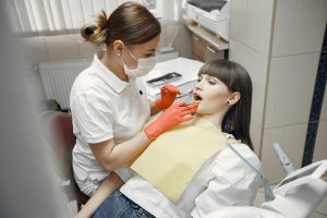 Dentist in red gloves examining a patient's teeth.