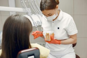 Dentist showing a tooth model to a child in a dental office.