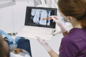 Dentist showing a dental X-ray to a patient on a laptop.