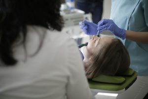Dentist in gloves treating a patient in a dental chair.