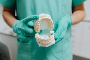 Dentist in gloves holding a dental model, relevant to Phoenix Invisalign.