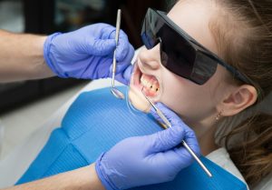 Child receiving a dental check-up wearing protective glasses.