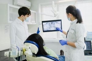 Dentists reviewing a dental X-ray with a patient in the chair.